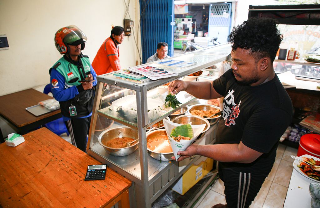 Riki, karyawan di rumah makan padang vegetarian Bundo Minang di kawasan Jelambar, Jakarta Barat, melayani pembelian daring, Rabu (27/7/2022). Bundo Minang menawarkan menu masakan khusus bagi vegetarian dengan bumbu khas Minang. 