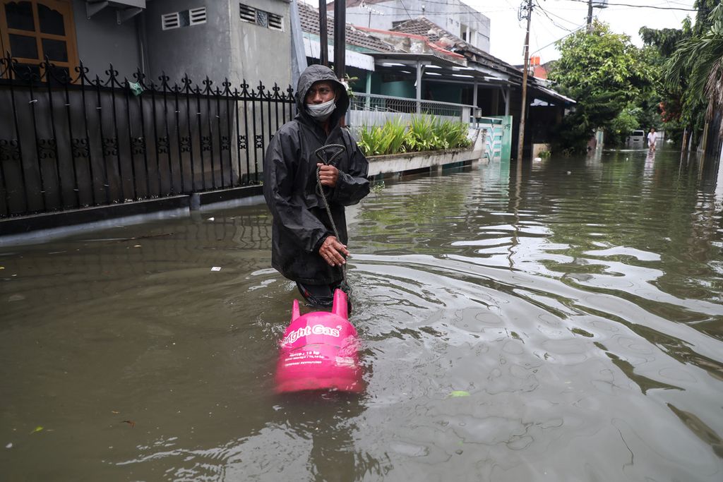 Sukirdhi, menembus banjir saat mengantarkan gas elpiji ke pelangganya yang terendam banjir di Panggung Lor, Semarang, Minggu (7/2/2021). Banjir yang terjadi sejak Sabtu (6/2/2021) kemarim belum sepenuhnya surut.