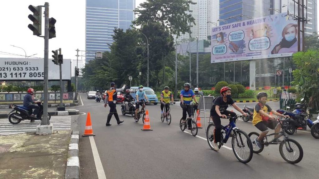 Petugas menghalau kendaraan bermotor yang hendak masuk ke ruas Jalan Sultan Iskandar Muda, Kebayoran Lama, Jakarta Selatan, Minggu (28/6/2020).