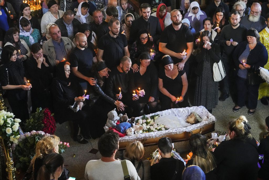 Kerabat menghadiri upacara pemakaman Liza (14) yang menjadi korban dari serangan Rusia di Gereja Ortodok, Vinnystsia, Minggu (17/7/2022). Anak-anak turut menjadi korban perang yang sudah berkecamuk hingga beberapa bulan ini. 