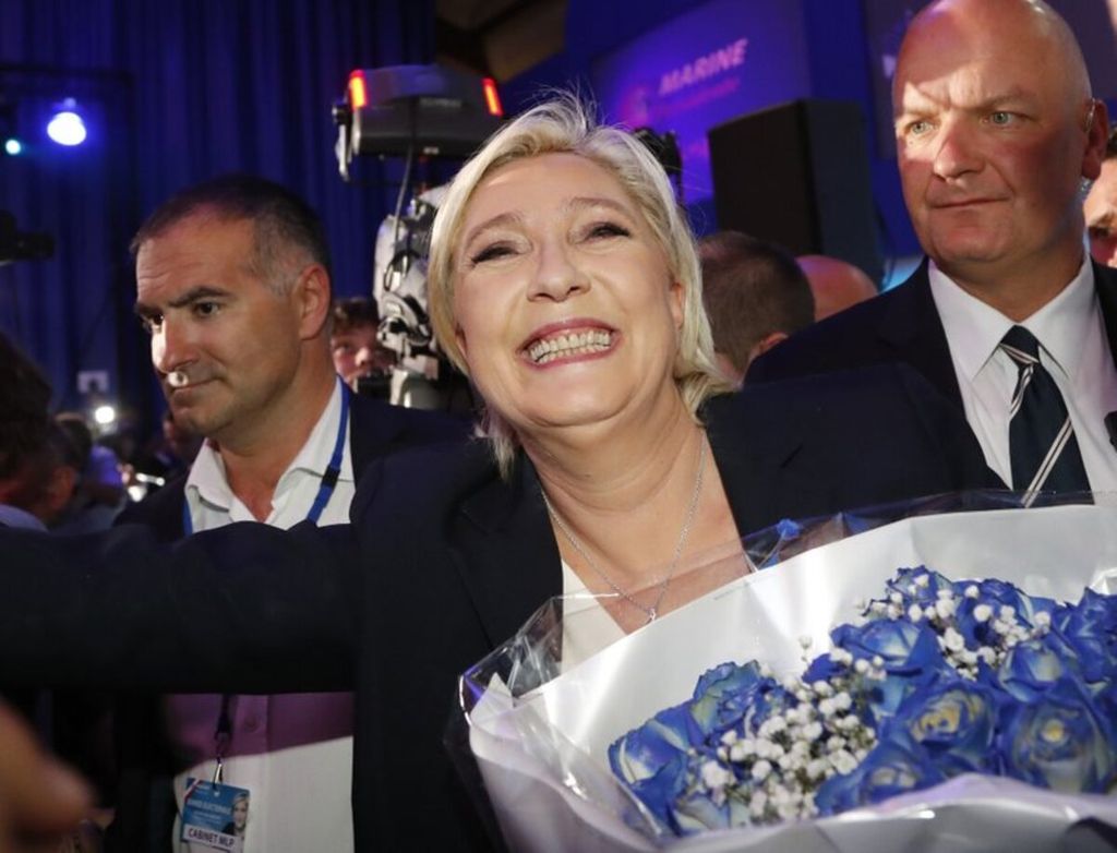 Marine Le Pen, politisi berhaluan kanan, bergembira bersama pendukungnya dengan dijaga oleh sejumlah pengawal, Minggu (23/4), di Paris, Perancis.