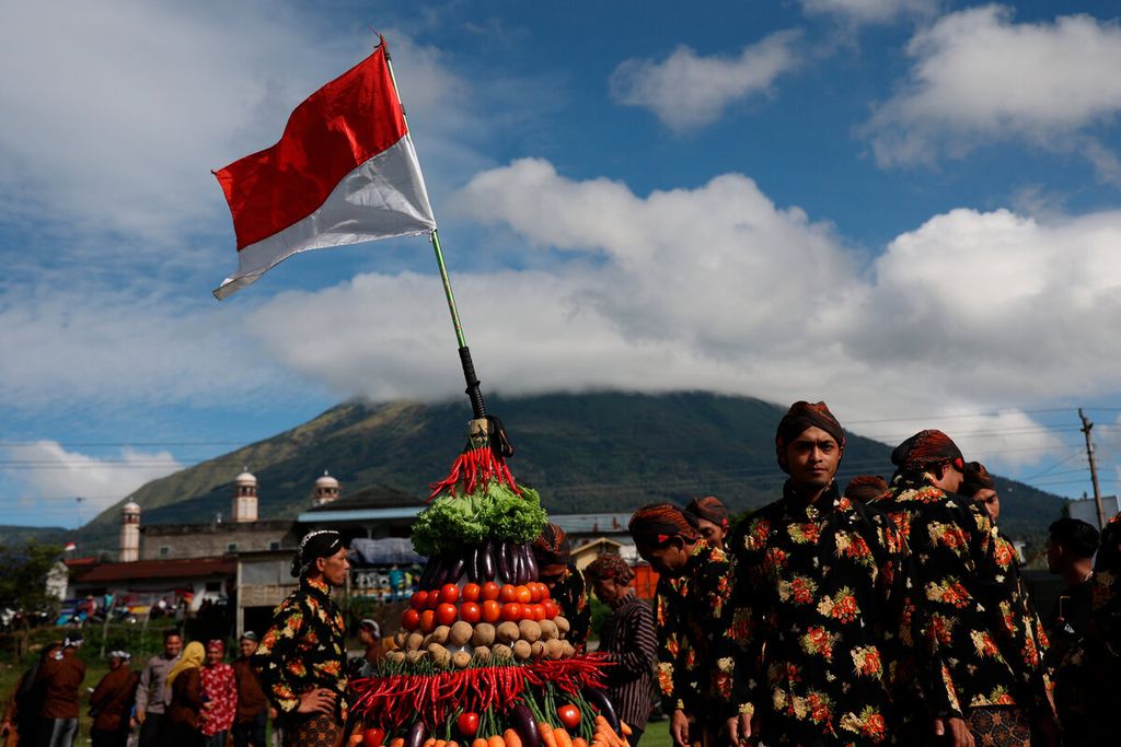 Warga menyiapkan gunungan hasil bumi dengan latar belakang Gunung Sindoro saat menyelenggarakan tradisi nyadran di Desa Kledung, Kecamatan Kledung, Kabupaten Temanggung, Jawa Tengah, Jumat (7/10/2022). 