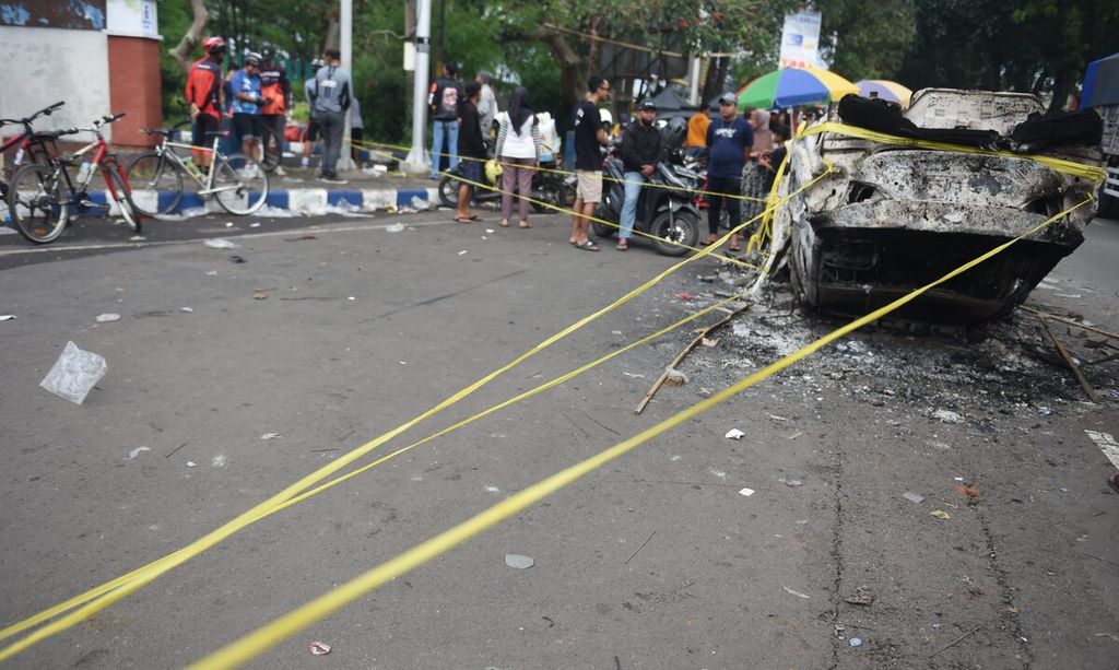 Bangkai mobil yang rusak terbakar saat kerusuhan sehari sebelumnya di Stadion Kanjuruhan, Kabupaten Malang, Jawa Timur, Minggu (2/10/2022). Kerusuhan terjadi saat berlangsung Liga 1 BRI antara Arema FC dengan Persebaya. Kerusuhan dimulai saat polisi menghalau suporter yang turun ke lapangan setelah Arema FC kalah 2-2. Gas air mata yang dilepaskan oleh polisi membuat kepanikan dan menyebabkan banyak penonton terinjak-injak dan kesulitan napas. Sebanyak 129 orang tewas dalam kejadian tersebut. 