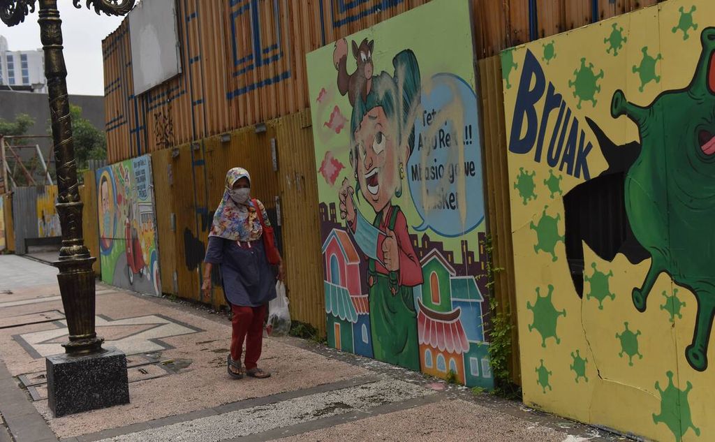 Warga melintas di depan mural bertema protokol kesehatan di Jalan Tunjungan, Kota Surabaya, Jawa Timur, Senin (21/2/2022). Mural yang sejatinya untuk mengingatkan warga agar patuh pada protokol kesehatan banyak dirusak oleh tangan yang tidak bertanggung jawab.