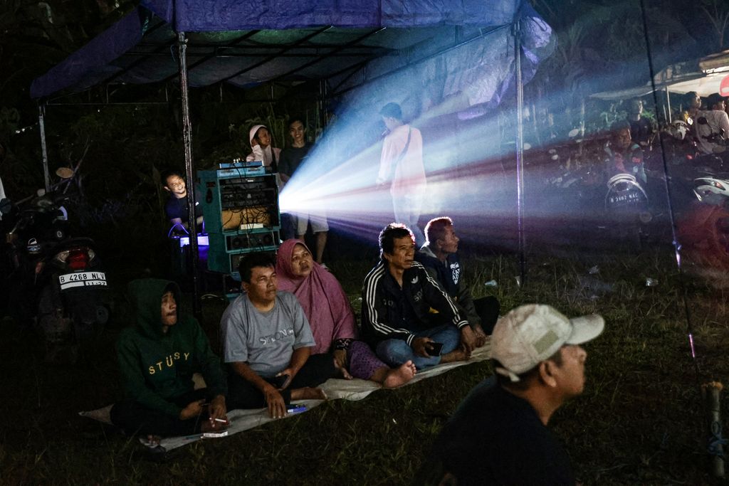Antusias warga menyaksikan film yang diputar dalam festival layar tancap di Babakan, Kecamatan Setu, Tangerang Selatan, Banten, Rabu (18/1/2023) malam. 