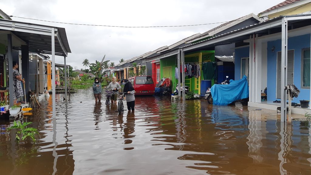 Warga melintasi banjir di kompleks perumahan di Kecamatan Banjarmasin Timur, Kota Banjarmasin, Kalimantan Selatan, Kamis (14/1/2021). Intensitas hujan yang tinggi menyebabkan banjir melanda sembilan dari 13 kabupaten/kota di Kalsel.
