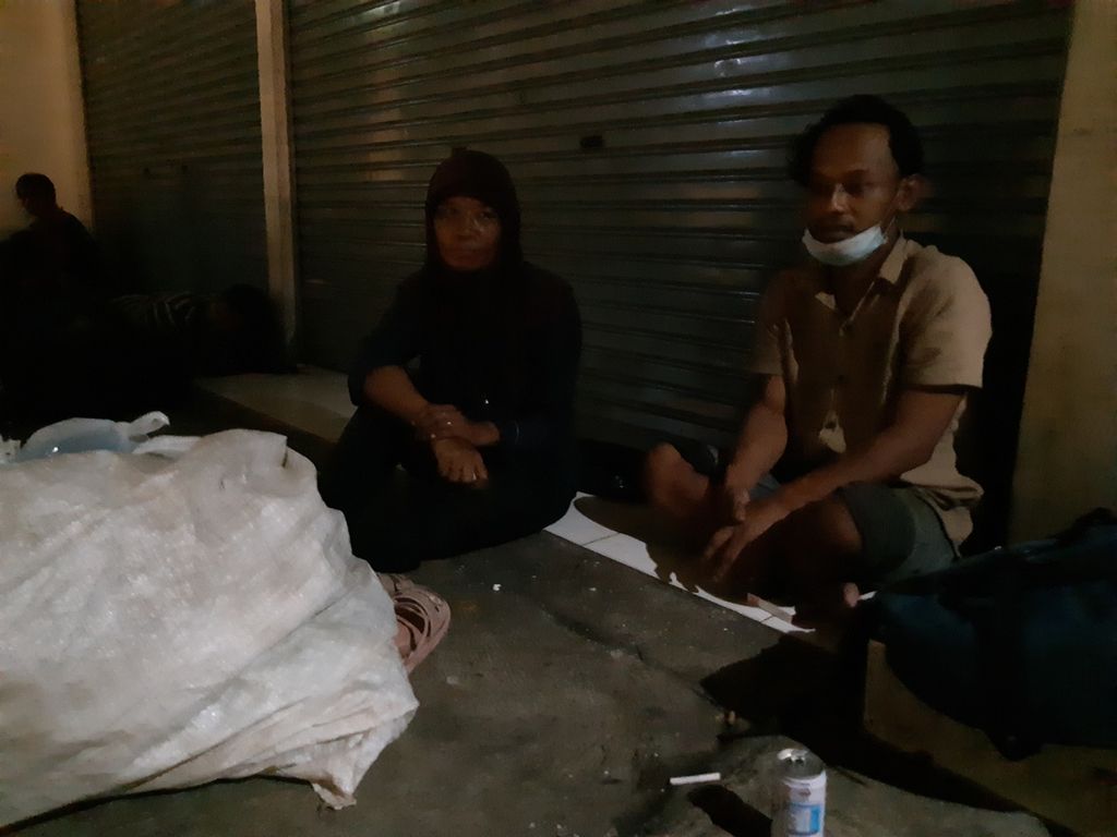Pasangan suami istri Andry (38) dan Iis (48) yang bekerja sebagai pemulung tengah beristirahat di sebuah ruko di dekat Pasar Palmerah, Jakarta Barat, pada Jumat (17/3/2023) malam.
