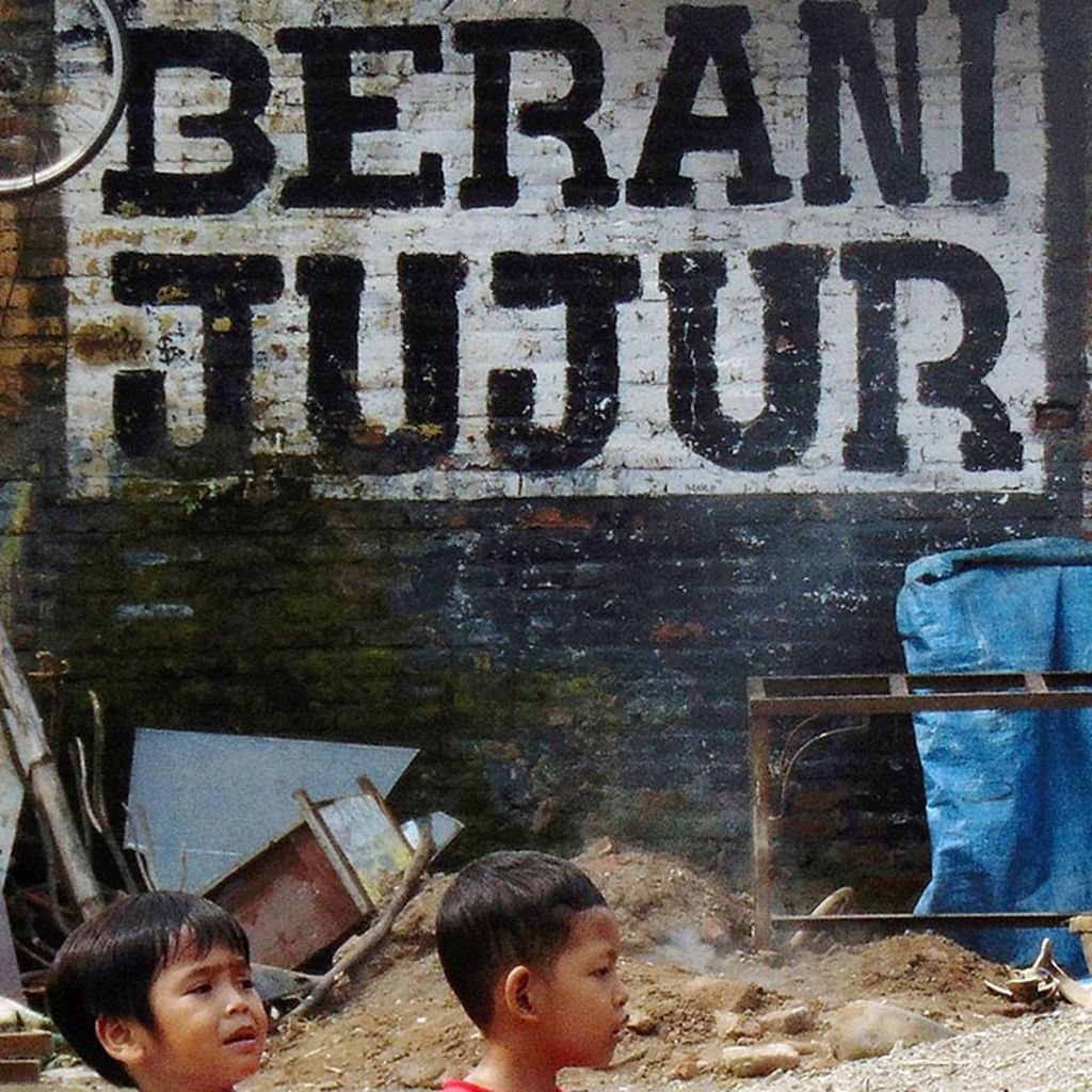 Dua bocah di Pondok Pesantren Buntet, Kabupaten Cirebon, Jawa Barat, melintasi mural berisi ajakan berani jujur di Buntet, Minggu (5/2). Sifat berani jujur dibutuhkan bangsa ini di tengah maraknya korupsi di lembaga pemerintah hingga lembaga peradilan. 