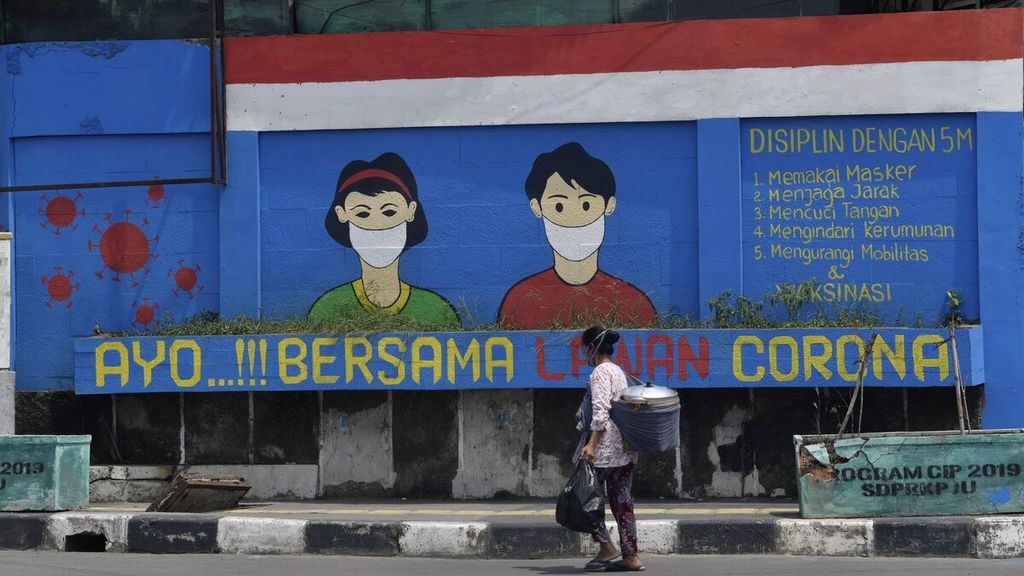 Penjual makanan keliling berjalan kaki melewati mural dengan pesan untuk melawan Covid-19 di Jalan Pakin, Jakarta Utara, Senin (23/8/2021). 