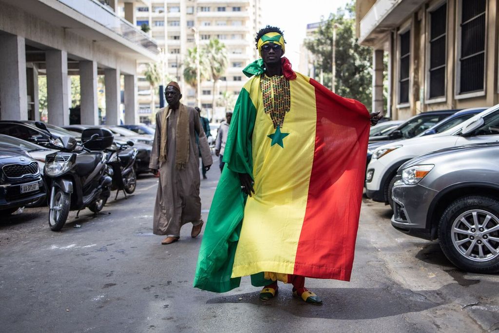 Seorang penggemar tim nasional Senegal mengenakan pakaian tradisional <i>boubou </i>bertema bendera Senegal di Dakar, Senegal, 1 Desember 2022. Senegal akan menghadapi Inggris pada laga 16 besar Piala Dunia Qatar 2022 di Stadion Al Bayt, Al Khor, Senin (5/12/2022) dini hari WIB.