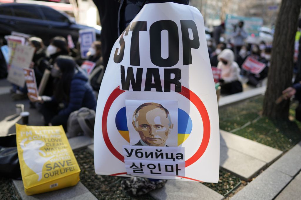 Poster bergambar Presiden Rusia Vladimir Putin dibawa pengunjuk rasa di Seoul, Korea Selatan, pada 24 Februari 2023. Pada Jumat (17/3/2023), Mahkamah Kriminal Internasional mengumumkan perintah penangkapan terhadap Putin.