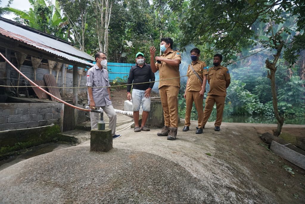 Jantje Sumelang (65, bertopi hijau) mendampingi perangkat Desa Tumaluntung, Minahasa Utara, Sulawesi Utara, di reaktor biogas di area peternakan babi miliknya, Senin (4/7/2022).