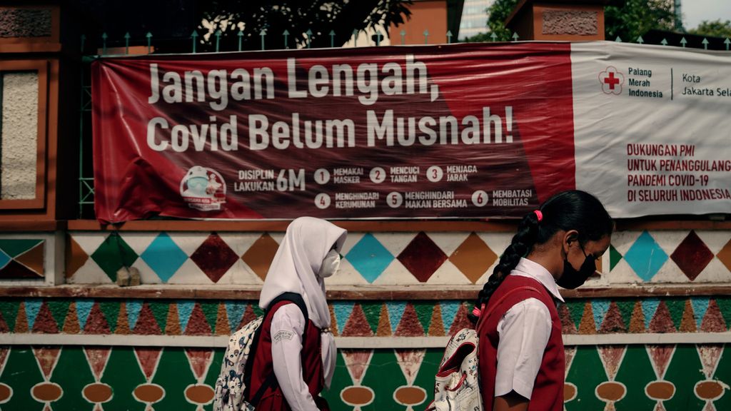 Pelajar pulang sekolah melewati spanduk protokol kesehatan di Setiabudi, Jakarta Selatan, Selasa (8/3/2022). 
