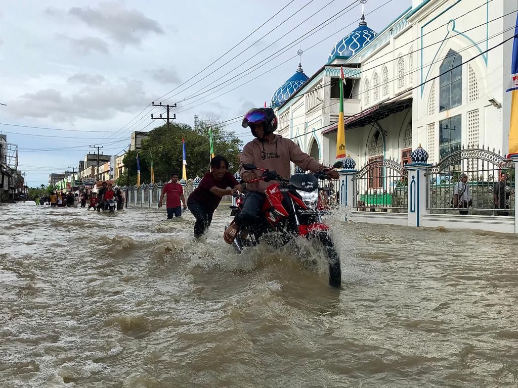 A motorcyclist was pushed by residents while crossing the national road in Lhoksukon City, North Aceh Regency, Aceh Province, Saturday (8/10/2022) which was flooded.