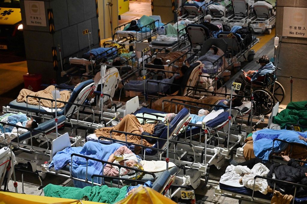 Sejumlah pasien Covid-19 terbaring di tempat tidur yang berada di luar Caritas Medical Centre, Hong Kong pada Rabu (16/2/2022). Mereka terpaksa ditempatkan di luar karena rumah sakit mulai kewalahan dengan membludaknya kasus baru Covid-19. 