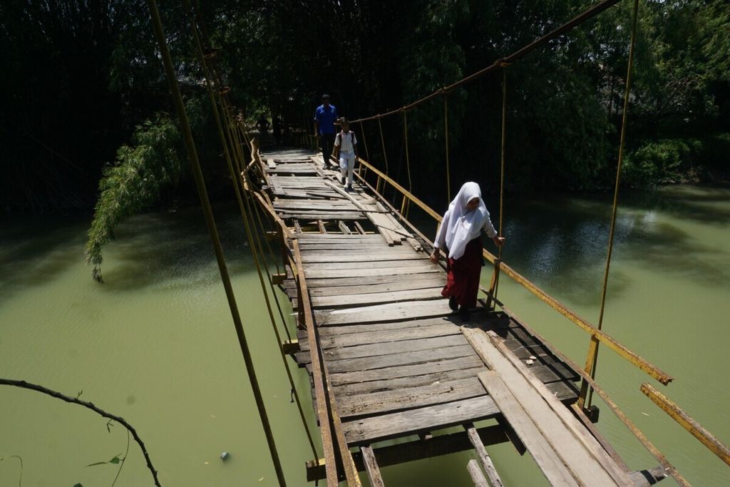 Siswa dan warga melintasi jembatan gantung dalam kondisi rusak di Desa Ketapang Aree, Kecamatan Delima, Kabupaten Pidie, Aceh, Selasa (17/9/2019). Anak-anak usia 12 tahun ke bawah di Pidie akan diimunisasi polio secara serentak untuk mencegah penyebaran virus polio. 