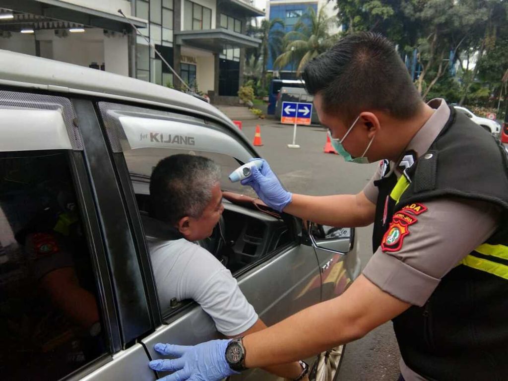 Petugas menggunakan <i>thermo gun </i>untuk mengukur suhu tubuh warga yang mengakses layanan di Polda Metro Jaya, Jakarta Selatan, Rabu (18/3/2020).