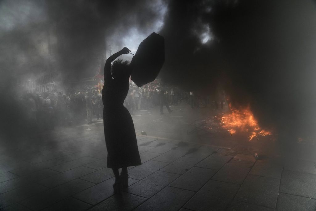 Seorang perempuan meneriakkan yel-yel anti-pemerintah sambil memegang payung di tengah kepulan asap tebal dalam unjuk rasa di Buenos Aires, Argentina, 10 Maret 2022. Unjuk rasa tersebut digelar untuk memprotes kesepakatan antara Pemerintah Argentina dan Dana Moneter Internasional (IMF) guna membayar utang sekitar 45 miliar dollar AS. 