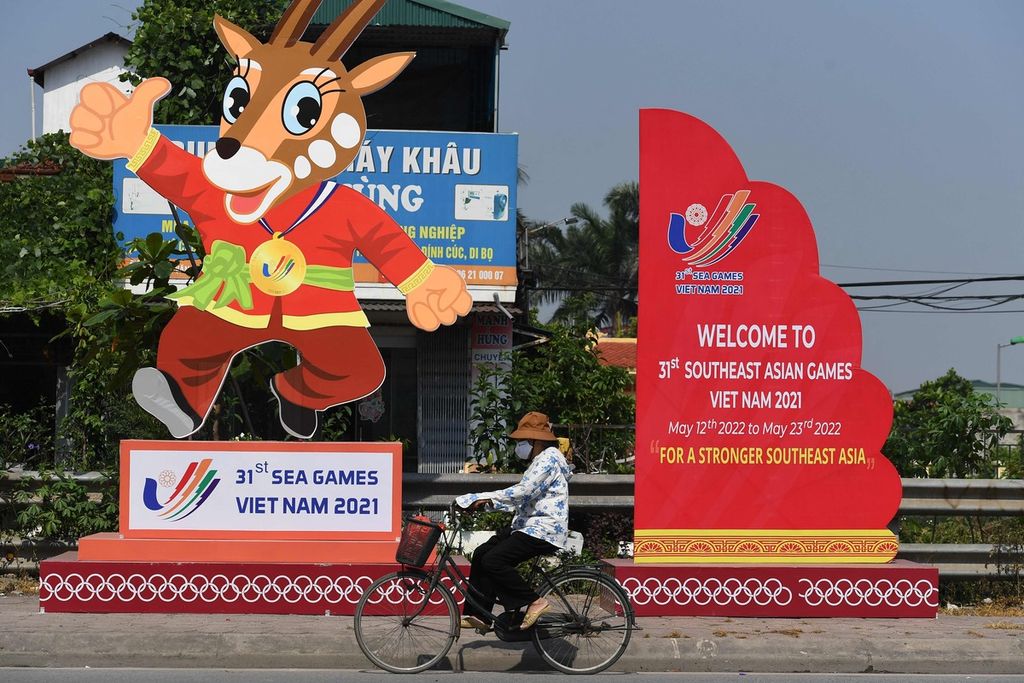 A woman rides a bicycle past a banner for the upcoming 31st Southeast Asian Games (SEA Games) in Hanoi on May 4, 2022, before the start of the multi-sport event on May 12. (Photo by Nhac NGUYEN / AFP)