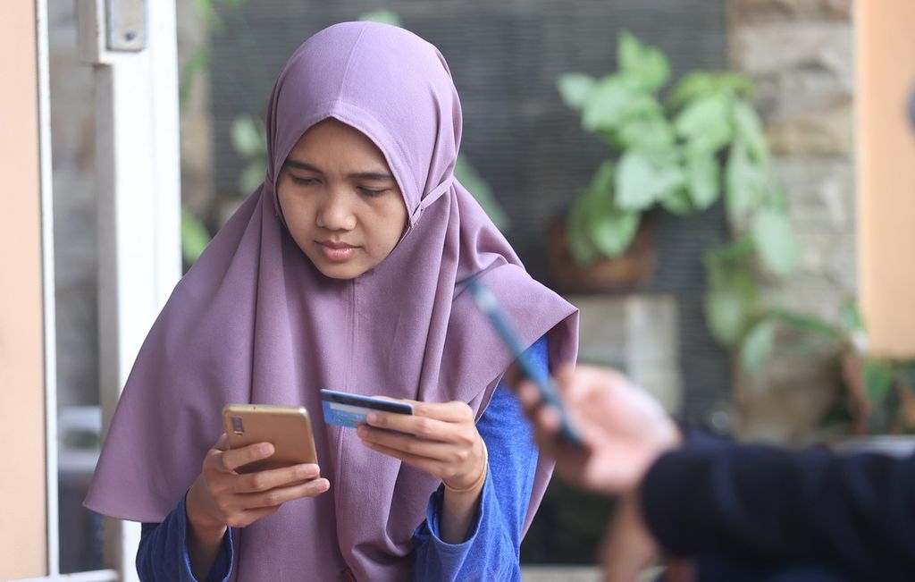 Rika Apriani melakukan transaksaksi elektronik melalui ponselnya di Serua, Depok, Jawa Barat, Minggu (11/9/2022). Data pribadi menjadi instrumen penting dalam semua lingkup dunia digital. Namun, sayangnya hingga kini sudah tidak terhitung jumlah data pribadi warga yang bocor dan diperjualbelikan. 
