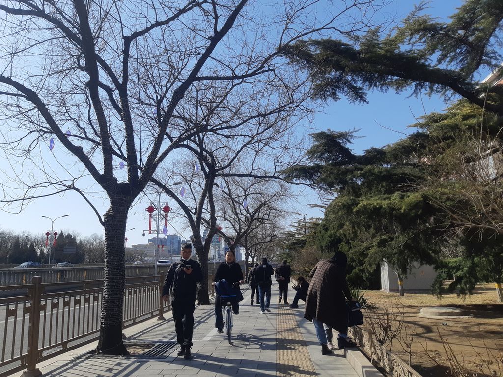 Warga berjalan kaki di sepanjang jalan Distrik Chaoyang, Beijing, China, Kamis (2/3/2023) sore. Aktivitas di Beijing, China, kembali menuju normal setelah pemerintah China mencabut kebijakan nihil Covid-19 atau Zero Covid Policy.