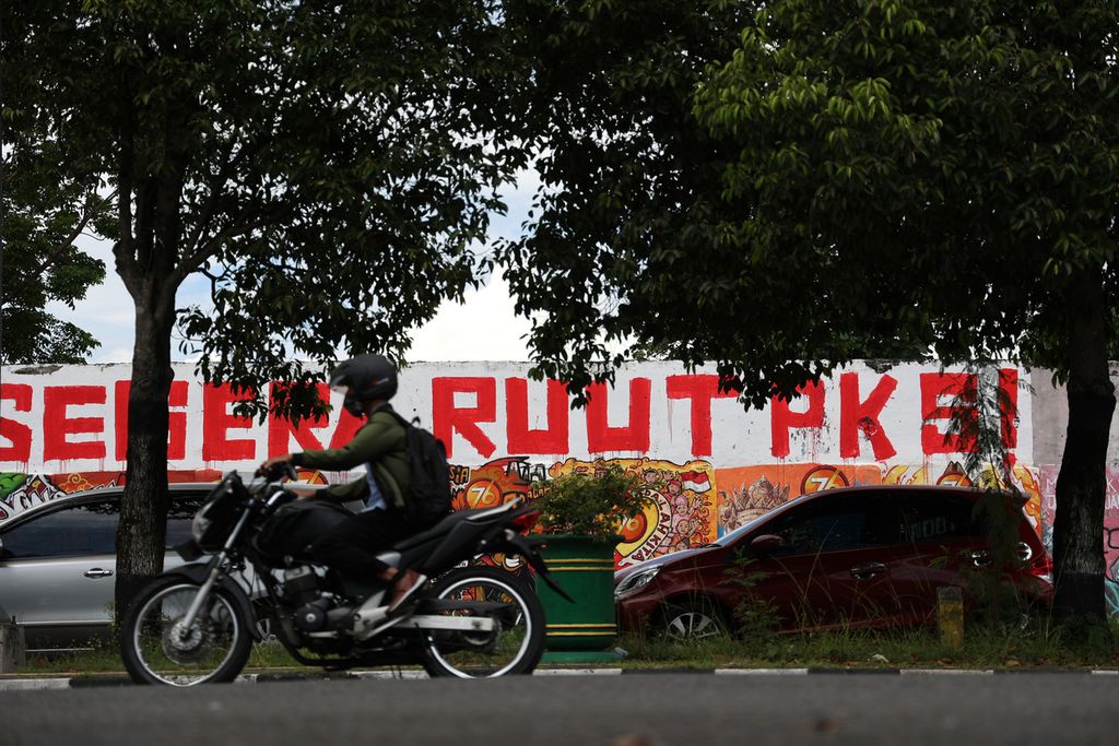 Mobil diparkir di depan mural berisi seruan untuk mendorong pengesahan Rancangan Undang-Undang Tindak Pidana Kekerasan Seksual yang dibuat di tembok Stadion Kridosono, Yogyakarta, Senin (10/1/2021). 