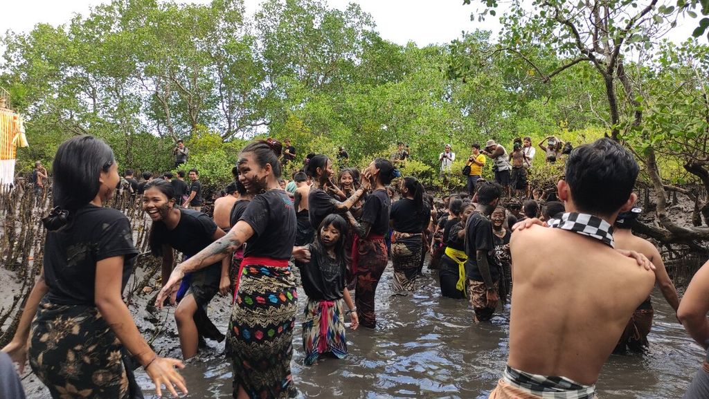 <i>Krama</i> (warga) dan <i>yowana </i>(pemuda dan pemudi) Desa Adat Kedonganan, Kedonganan, Kuta, Kabupaten Badung, saling membalurkan lumpur hutan bakau ketika mengikuti tradisi <i>mabuug-buugan </i>di tengah hutan mangrove Taman Hutan Raya Ngurah Rai, Kamis (23/3/2023).