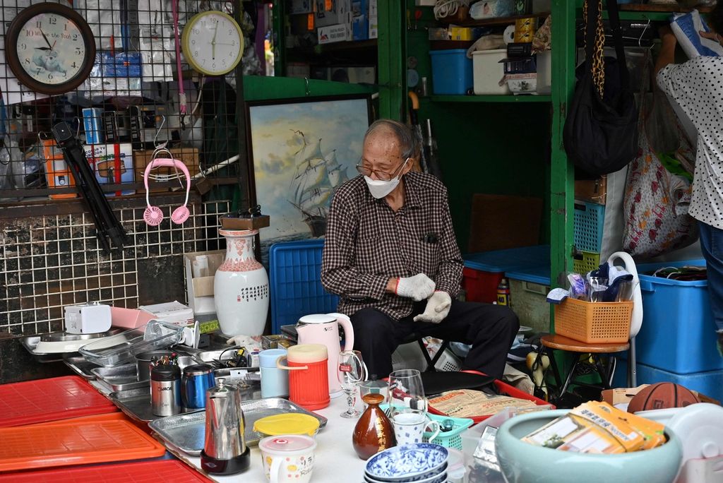 Seorang pedagang tengah menunggui dagangannya di sebuah emper pertokoan di Kowloon, Hong Kong pada Minggu (4/12/2022).