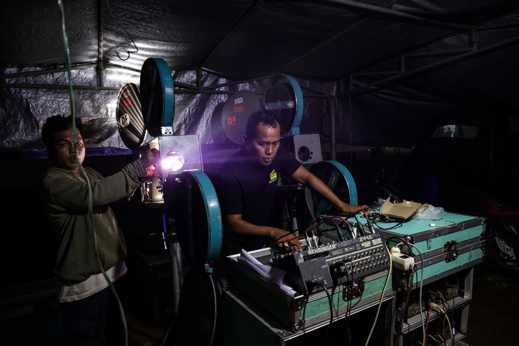 Petugas operator mengoperasikan proyektor yang memutar film seluloid 35 mm dalam festival layar tancap di lapangan di Babakan, Kecamatan Setu, Tangerang Selatan, Banten, Rabu (18/1/2023) malam. Kegiatan tersebut dalam rangka syukuran memperingati hari ulang tahun komunitas pencinta film LCD Tangerang Selatan.