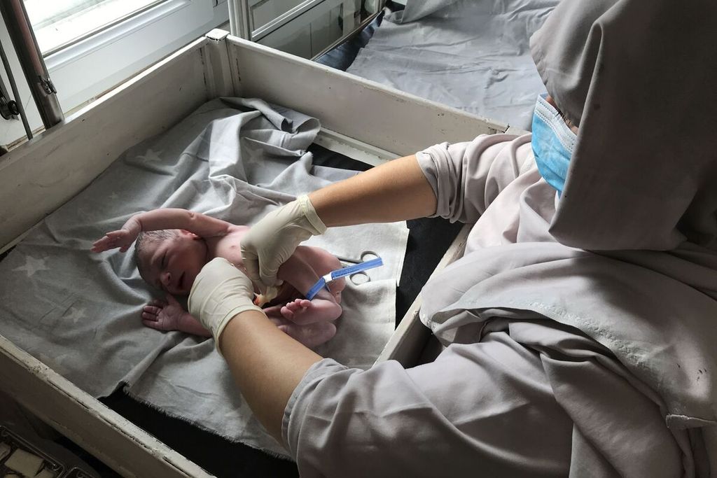 Seorang bidan dari lembaga amal Dokter Lintas Batas (MSF) memeriksa bayi yang baru lahir di rumah sakit bersalin MSF di Khost, Afghanistan, 9 Agustus 2018. 