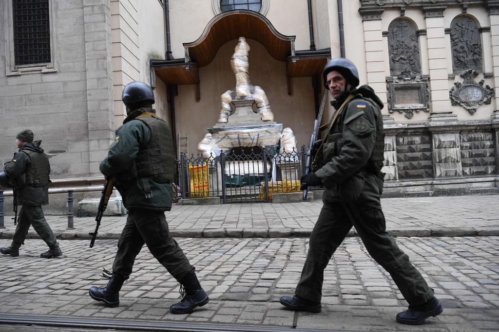 Prajurit Ukraina berjalan melintas di depan patung-patung yang dibungkus plastik yang berada di bagian depan Archcathedral Basilica of the Assumption of the Blessed Virgin Mary atau yang dikenal sebagai Katedral Latin di Lviv pada 5 Maret  2022.