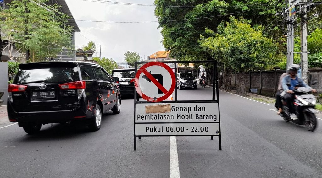 Plang pengumuman penerapan sistem ganjil-genap dan pembatasan mobil barang dipasang di tengah Jalan Raya Sesetan, Denpasar Selatan, Bali, Jumat (11/11/2022).
