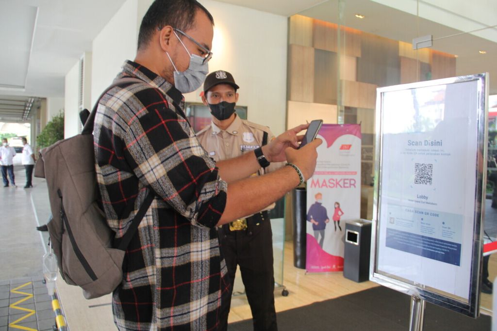 Pengunjung memindai QR Code Aplikasi Peduli Lindungi sebelum masuk ke Hotel Grand Zuri Malioboro, Kota Yogyakarta, Rabu (22/12/2021). 
