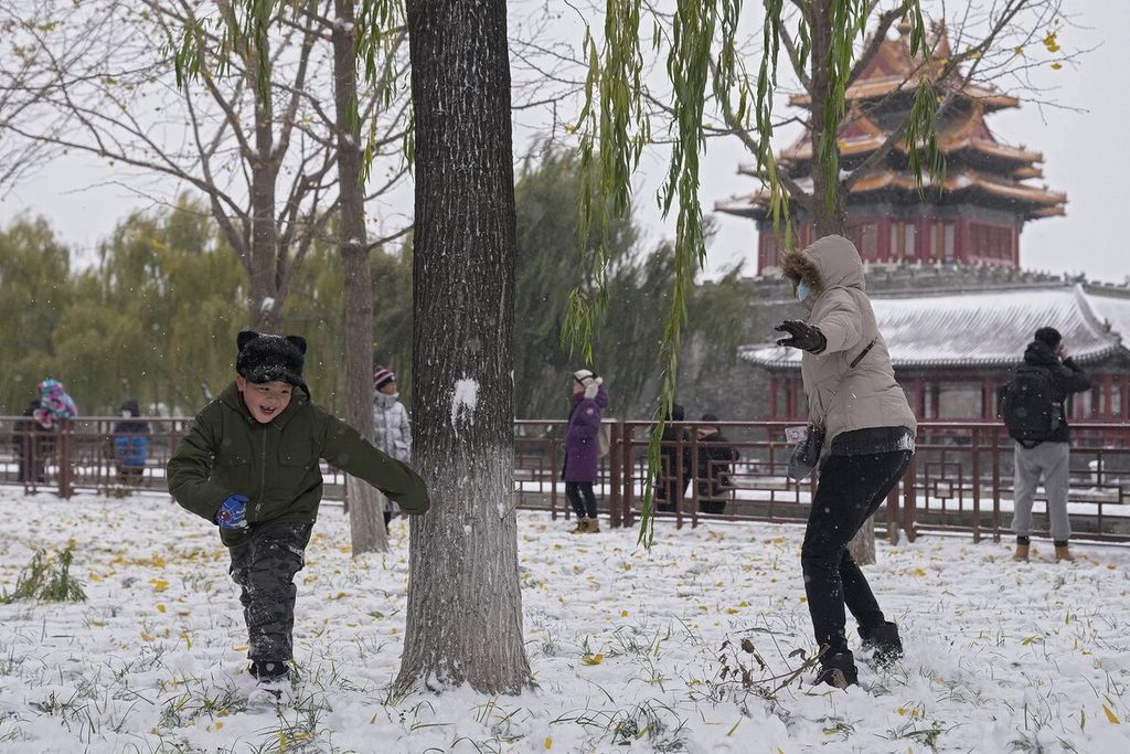 Anak-anak bersama anggota keluarganya bermain salju di dekat Kota Terlarang, Beijing, China, Minggu (7/11/2021). Ratusan ribu wisatawan menikmati tempat-tempat wisata bersalju di Beijing seperti Kota Terlarang dan Universal Studios Resort, meskipun pemerintah memberlakukan pembatasan terkait Covid-19. 