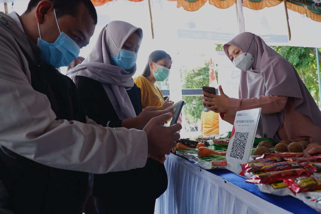 Pengunjung menggunakan pembayaran non-tunai untuk membayar produk yang dibeli pada kegiatan Pasar Rakyat Ramadhan yang diselenggarakan Kantor Perwakilan Bank Indonesia Provinsi NTB dan Pemerintah Kota Mataram di Lapangan Sangkareang, Kota Mataram, Nusa Tenggara Barat, Senin (11/4/2022). 