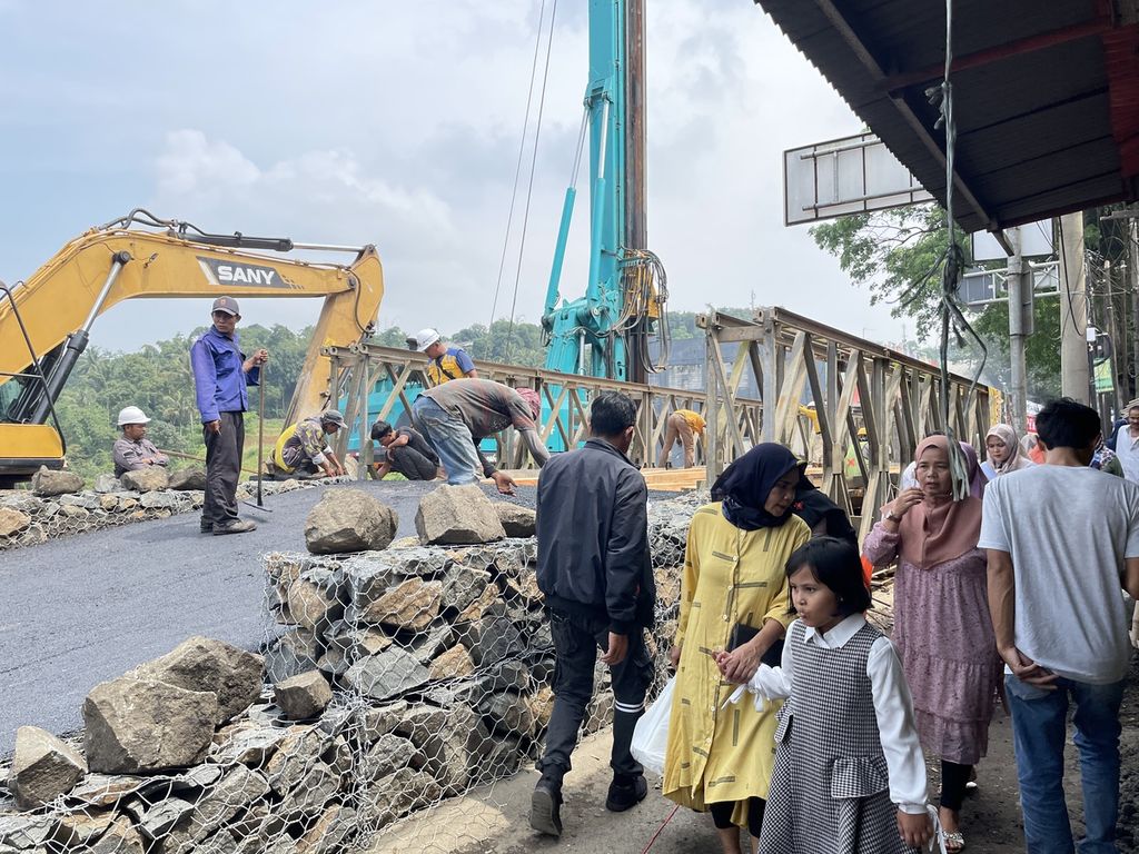 Celah antara jembatan dan ruko digunakan sebagai jalan untuk warga melintas setelah longsornya Jembatan Cikereteg di jalan nasional Ciawi-Benda, Kabupaten Bogor, Jawa Barat, yang longsor pada Senin (27/2/2023).