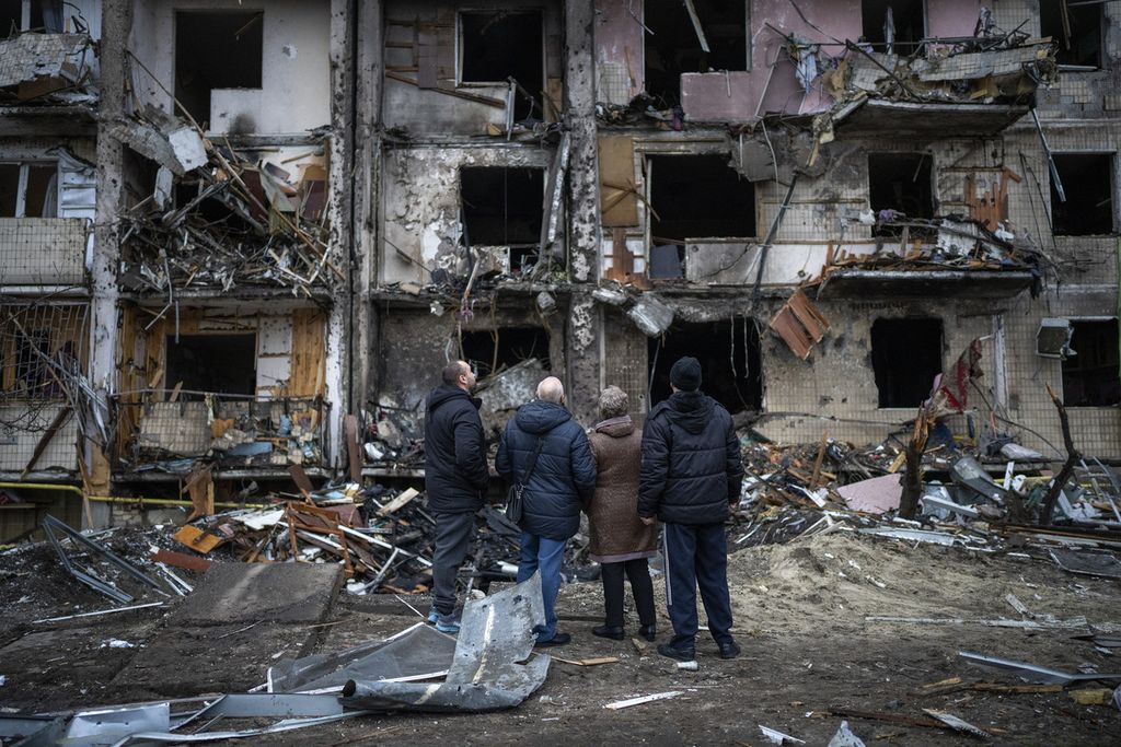 Sejumlah warga melihat bangunan tempat tinggal mereka yang rusak akibat serangan roket di Kiev, Ukraina, Jumat (25/2). Hanya berselang 12 jam setelah perintah invasi dikeluarkan Presiden Rusia Vladimir Putin, militer Rusia telah berhasil mengepung Ibu Kota Ukraina, Kiev.