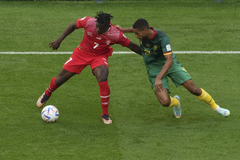 Pemain Swiss, Breel Embolo (kiri), berebut bola dengan Jean-Charles Castelletto dari Kamerun saat bertanding di babak fase Grup G Piala Dunia 2022 di Stadion Al Janoub, Qatar, Kamis (24/11/2022). Swiss menang 1-0.