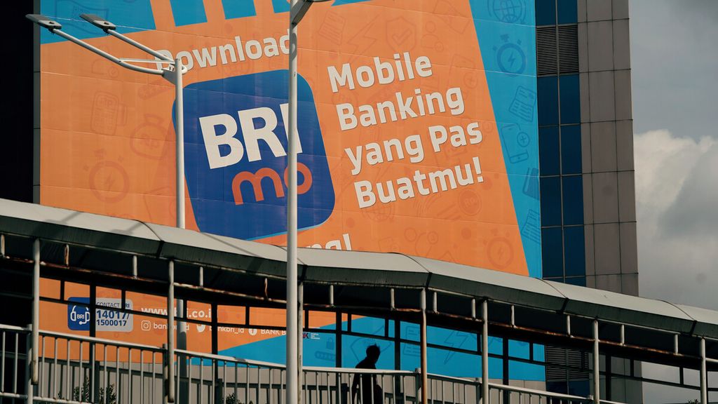 Warga melintasi baliho ajakan untuk mengunduh aplikasi digital BRI di Jalan Sudirman, Jakarta Pusat, Minggu (6/2/2022). 