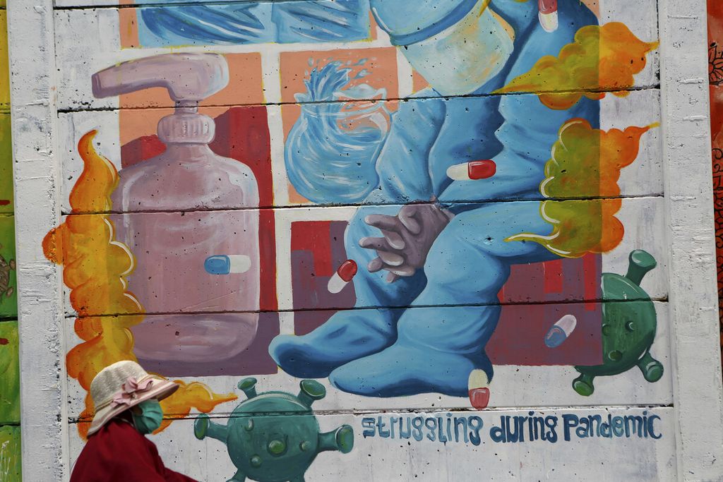 Warga melintasi mural bergambar tenaga kesehatan bertema Pejuang Masa Kini di Jatiasih, Kota Bekasi, Jawa Barat, Minggu (14/11/2021).  Selain untuk mengunjungi kota, dengan mural tersebut juga mengajak warga untuk terus terhubung dengan protokol kesehatan. 