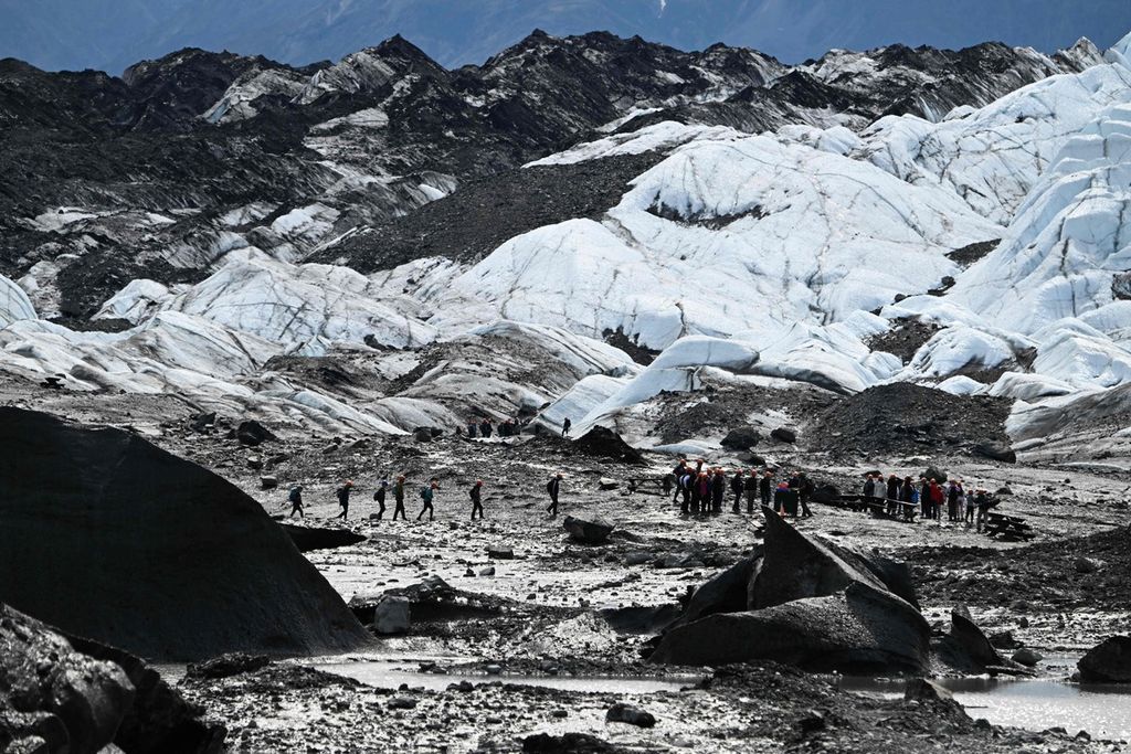 Sekelompok pengunjung melintasi gletser dalam tur wisata di gletser Matanuska, sepanjang 43,4 kilometer yang mengalirkan air ke Sungai Matanuska pada 10 Juli 2022, sekitar 161 kilometer timur laut dekat Palmer, Alaska. 