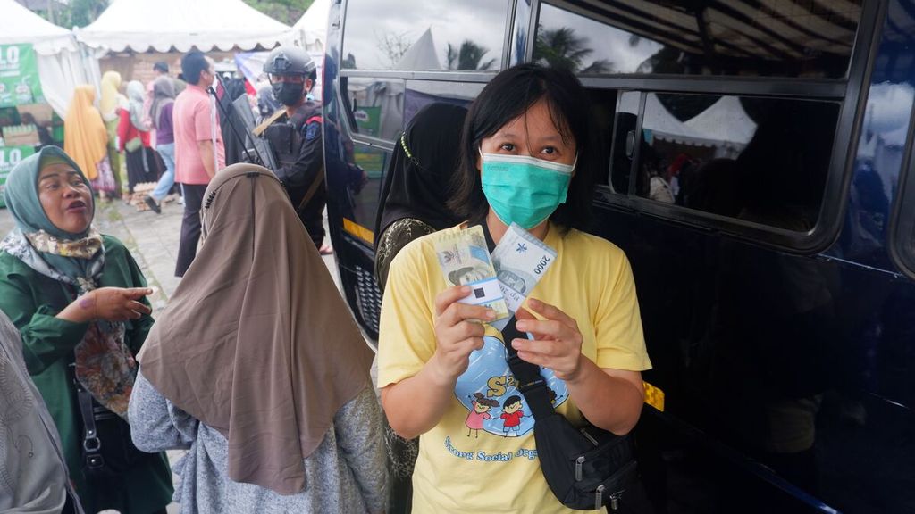 Seorang warga memperlihatkan uang baru yang didapatnya dari penukaran di mobil layanan kas keliling Bank Indonesia di Lapangan Taman Kamboja, Kota Banjarmasin, Kalimantan Selatan, Senin (14/11/2022). 