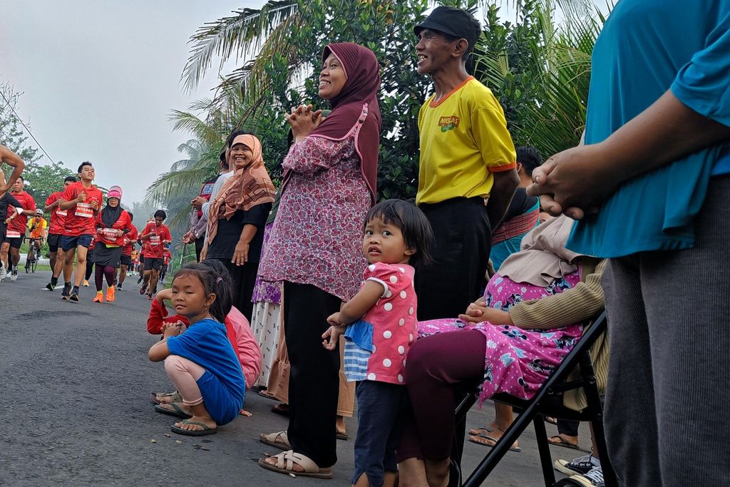 Warga menonton para pelari yang menyelesaikan Borobudur Marathon 2022 Powered by Bank kategori Tilik Candi yang melewati depan rumah mereka di sekitar kompleks Candi Borobudur, Magelang, Jawa Tengah, Minggu (12/11/2022). Sebanyak 4.552 pelari mengikuti lomba lari dengan jarak 21,097 kilometer atau separuh maraton.