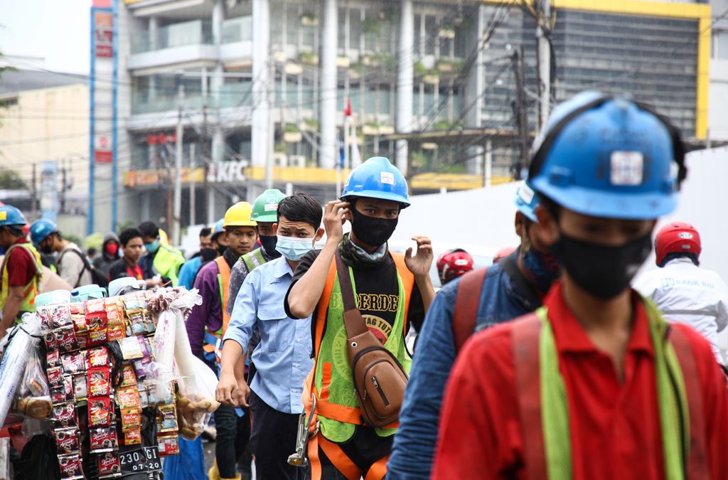 Pekerja proyek properti berjalan menuju tempat kerja mereka di kawasan Bendungan Hilir, Jakarta Pusat, Selasa (8/12/2020). Kondisi ketenagakerjaan di Indonesia terdisrupsi akibat pandemi Covid-19. 