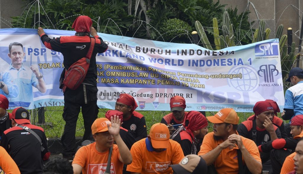 Massa buruh dari berbagai serikat pekerja berunjuk rasa di depan Gedung DPR/MPR, Jakarta, Rabu (15/6/2022). Dalam aksi yang diikuti ribuan buruh tersebut mereka kembali menyerukan penolakan atas revisi UU Pembentukan Peraturan Perundang-undangan (UU P3) dan penolakan UU Cipta Kerja. Para buruh juga menyerukan akan melakukan mogok kerja nasional jika DPR tidak mencabut revisi UU P3. KOMPAS/RADITYA HELABUMI 15-06-2022