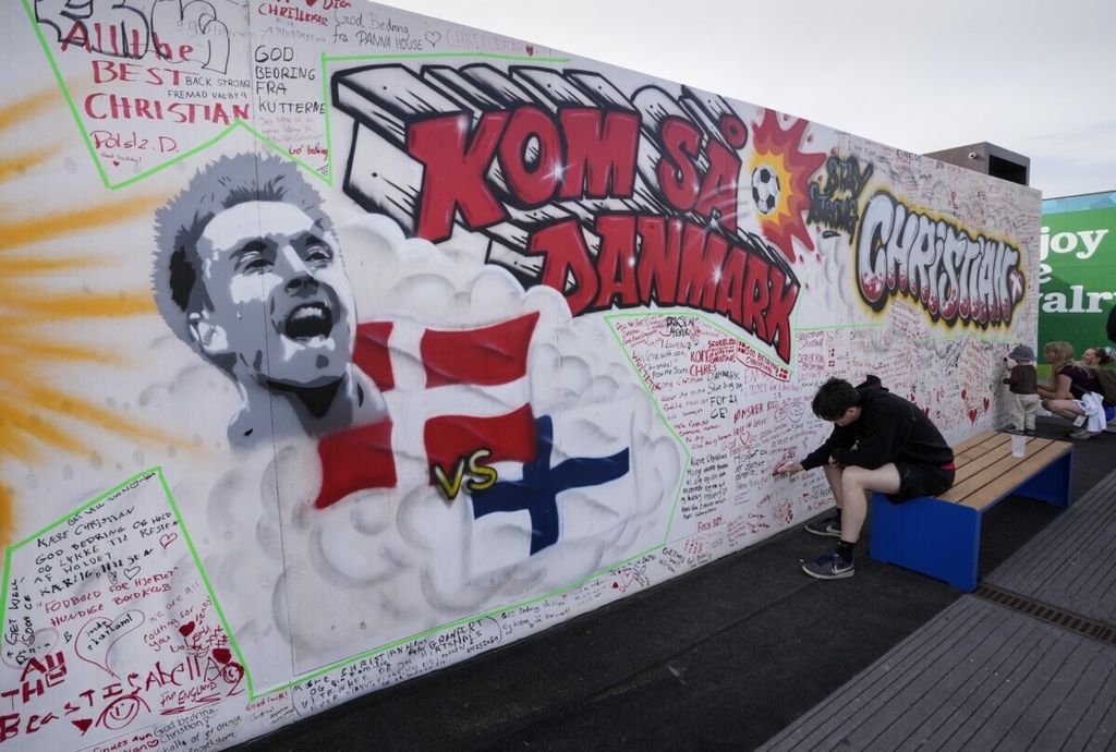 Warga menuliskan pesan dalam mural untuk kesembuhan gelandang Denmark, Christian Eriksen, di Kopenhagen, Denmark, 14 Juni 2021. Eriksen akan melanjutkan karier sepak bolanya bersama klub Liga Inggris, Brentford, setelah pemasangan alat ICD di jantungnya.