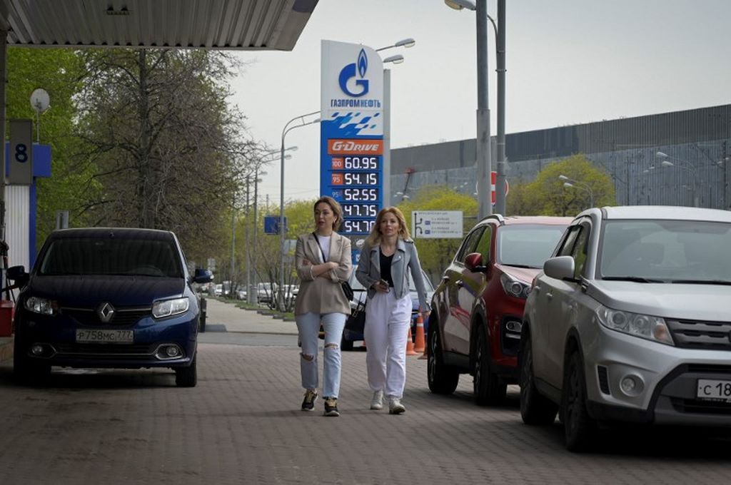 Dua wanita ini melintasi area stasiun pengisian bahan bakar umum milik produsen minyak Rusia, Gazprom Neft, di salah satu sudut kota Moskwa, 11 Mei 2022. 