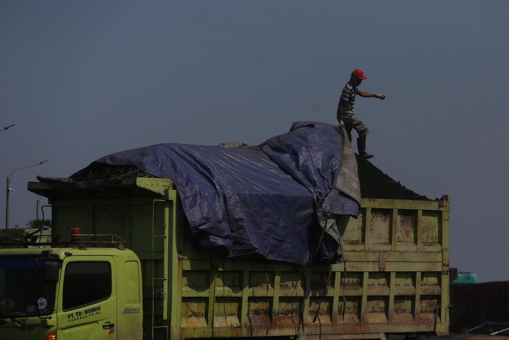 Pekerja menutup batubara asal Kalimantan dengan terpal di Pelabuhan KCN Marunda, Jakarta Utara, Rabu (5/1/2022). 