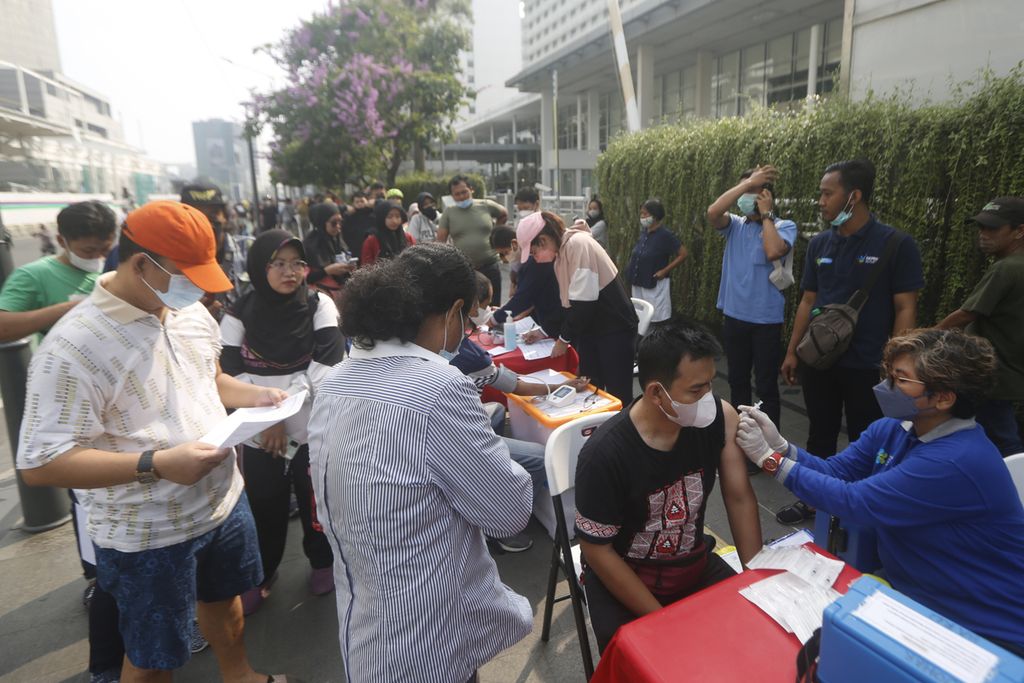 Warga secara bergantian menjalani vaksinasi Covid-19 di kawasan Bundaran HI, Jakarta, saat pelaksanaan hari bebas kendaraan bermotor Minggu (31/7/2022). 