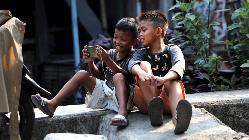 Anak-anak bercengkerama dengan gawai di kawasan Cideng, Jakarta Pusat, Rabu (18/7/2018). Penggunaan gawai oleh anak-anak memerlukan pengawasan, panduan, dan pembatasan dari orangtua untuk mencegah dampak negatif dari paparan media sosial dan gim daring.